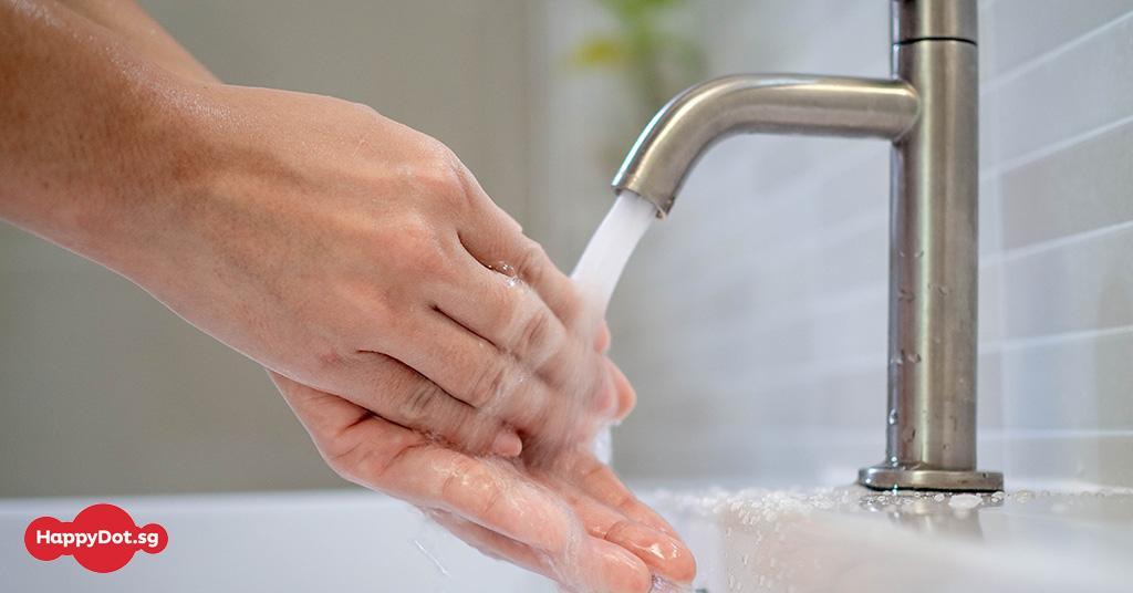 A person washing hands using tap